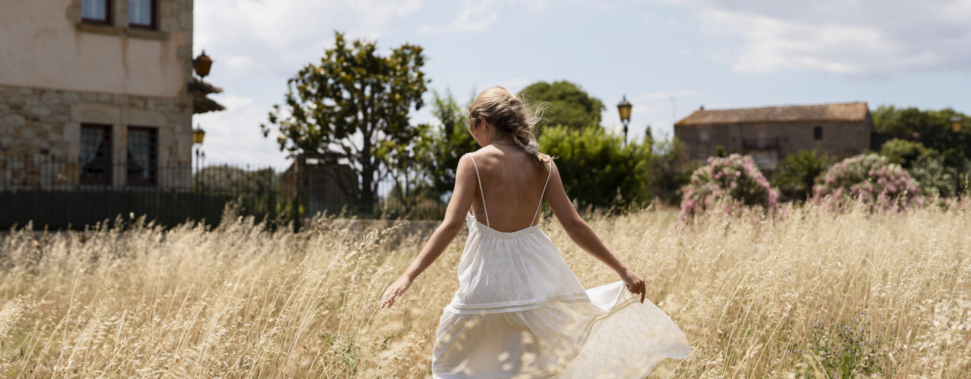 Woman strolling through a straw field in a white dress