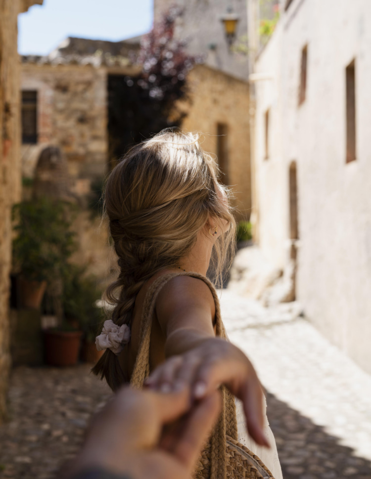 Woman walking hand in hand through the cobbled streets of Banyalbufar