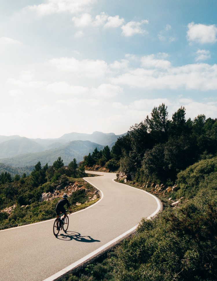 Cyclist on the road surrounded by mountains